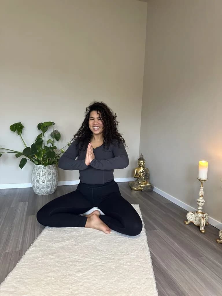 Yvonne sitzt lächelnd in einer ruhigen Yoga-Haltung